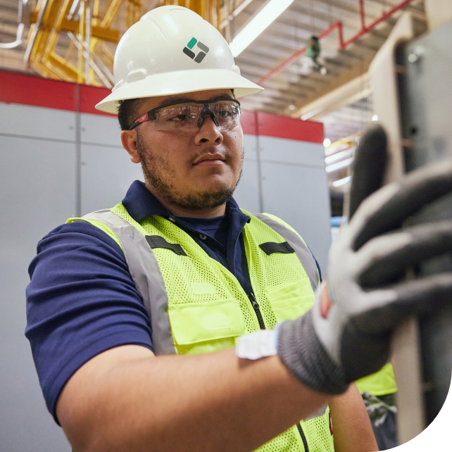 Modignet service technician in a mechanical room wearing PPE.